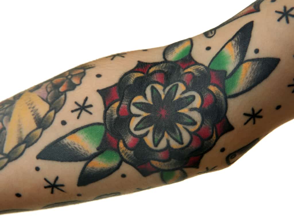 Bold Black and Red Rose with Geometrical Petals surrounded by Stars and Dots Forearm Tattoo | selftattoo.com