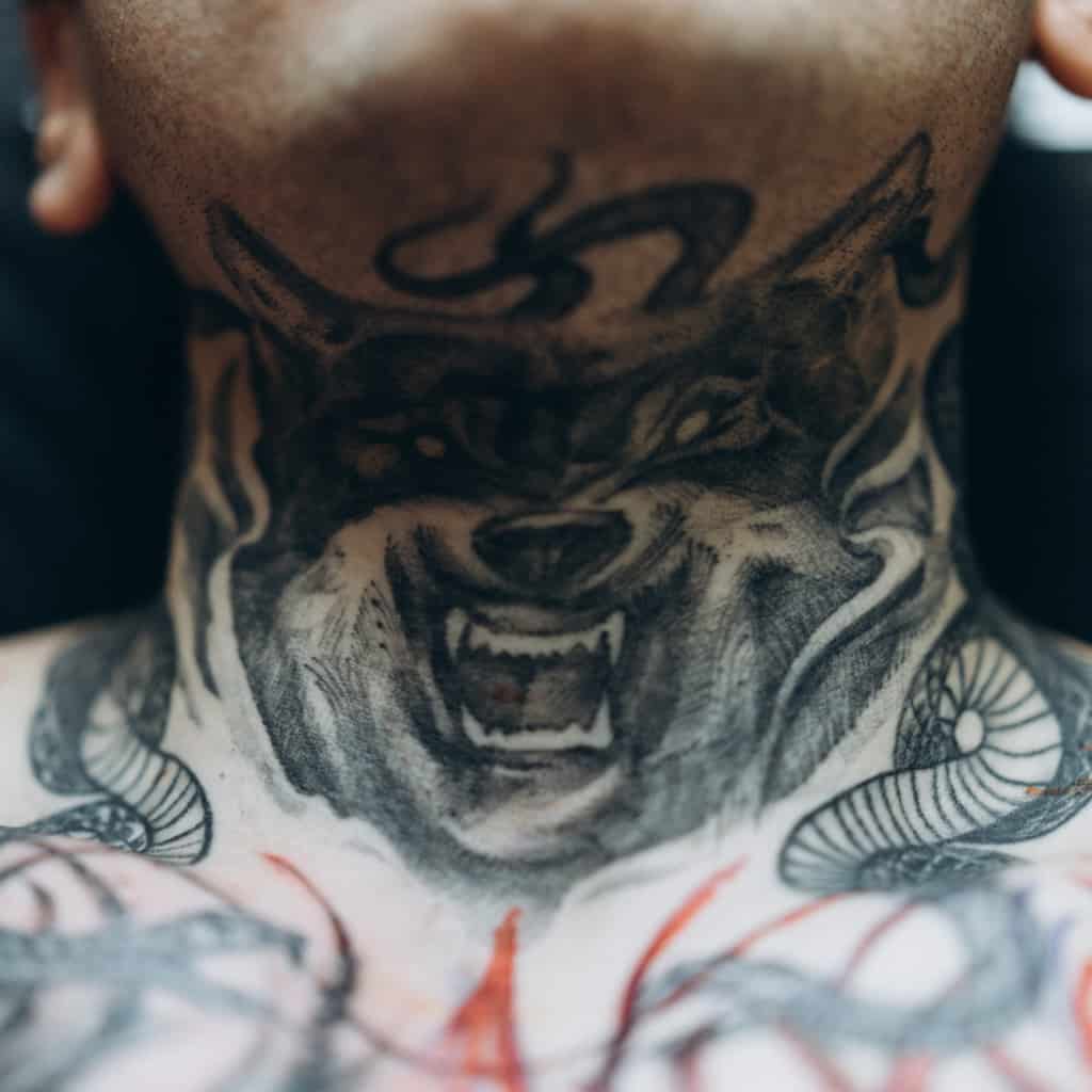 Fierce Black and Gray Wolf Head with a Snarling Expression Front of Neck Tattoo | selftattoo.com