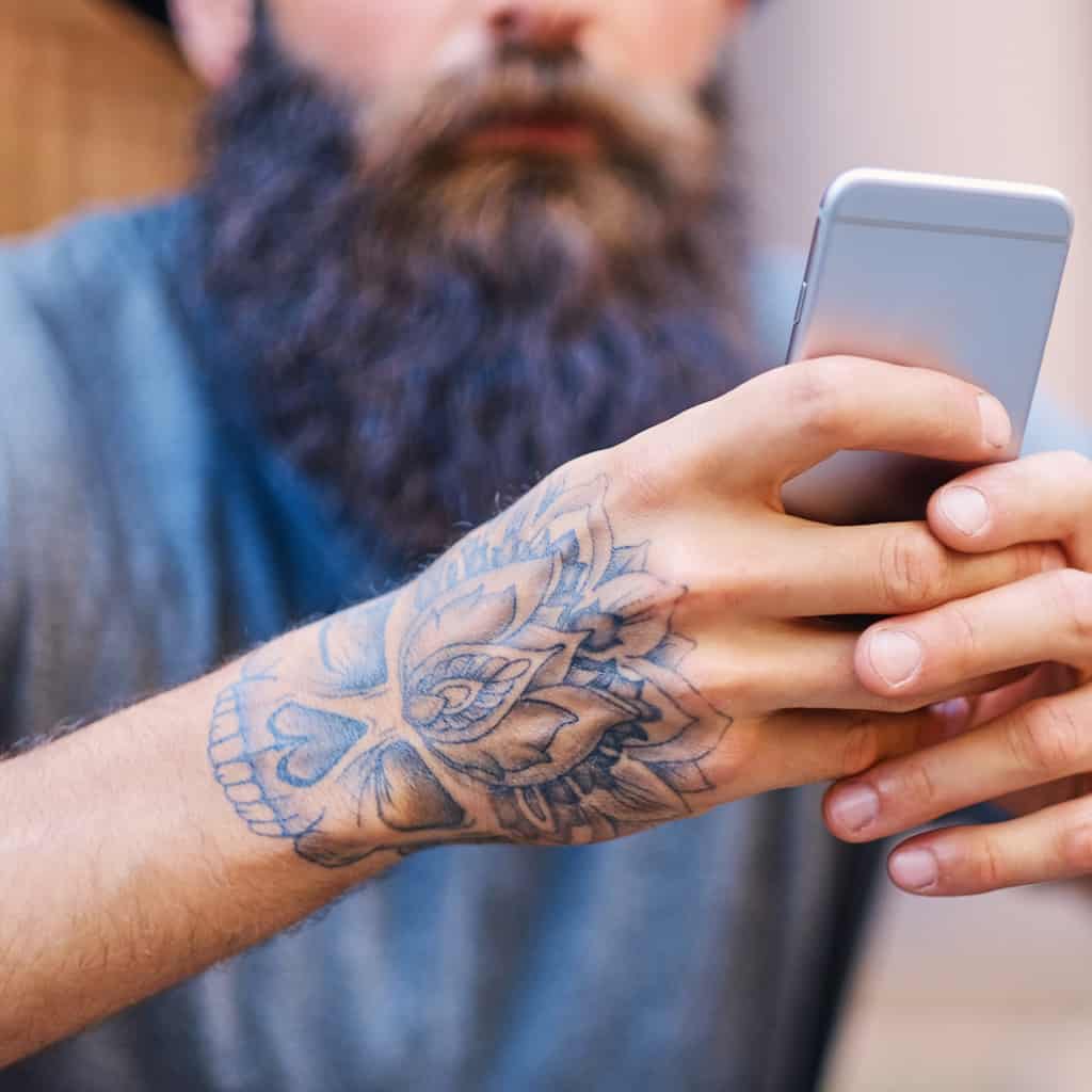 Detailed Black and Gray Half Skull with a Floral Top Hand Tattoo | selftattoo.com