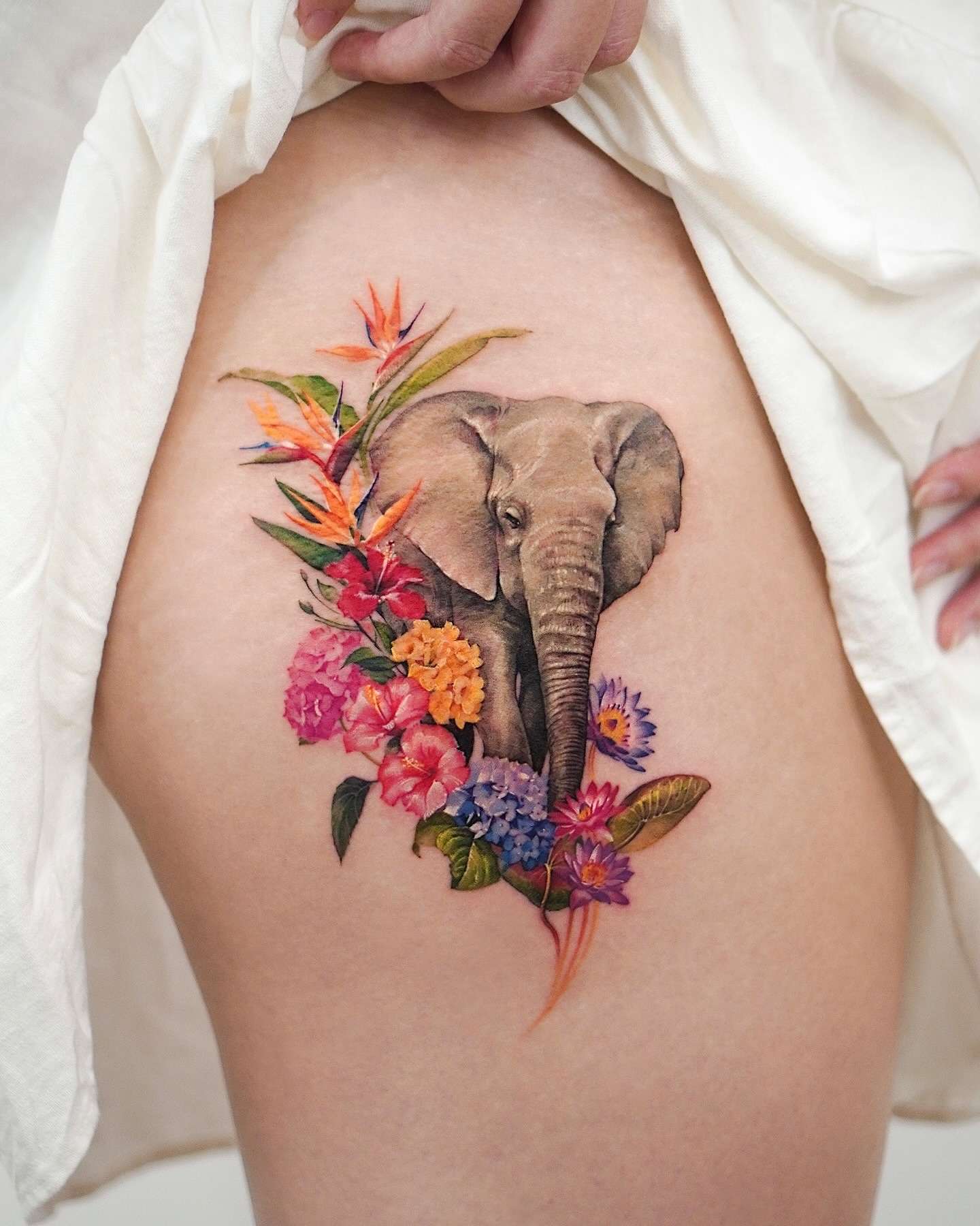 Realistic Elephant surrounded by Colorful Flowers Hip Tattoo | selftattoo.com