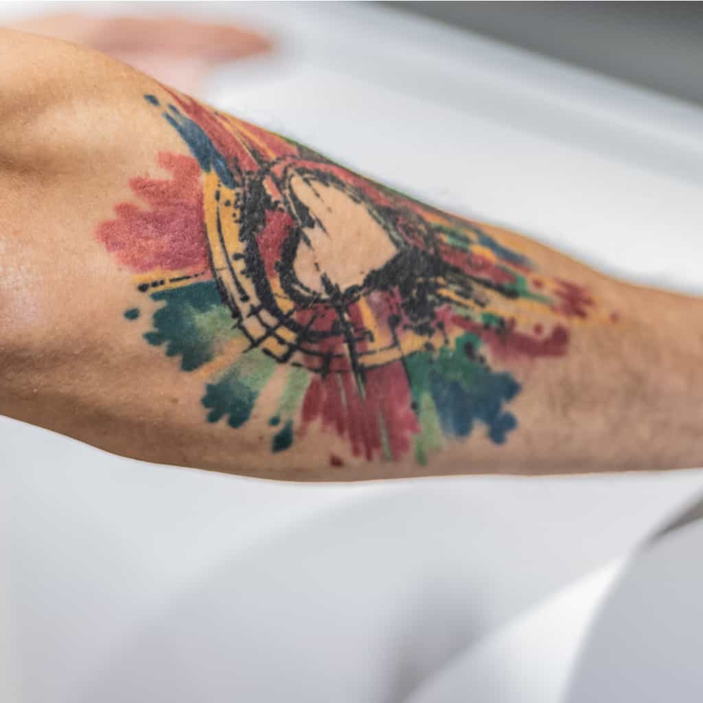 Sketch Style Outline of a Heart surrounded by Splashes of Watercolor Forearm Tattoo | selftattoo.com