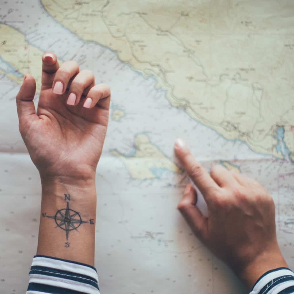 Small Simple Bold Black Linework of a Compass Rose with Cardinal Directions (N, S, E, W) Wrist Tattoo | selftattoo.com