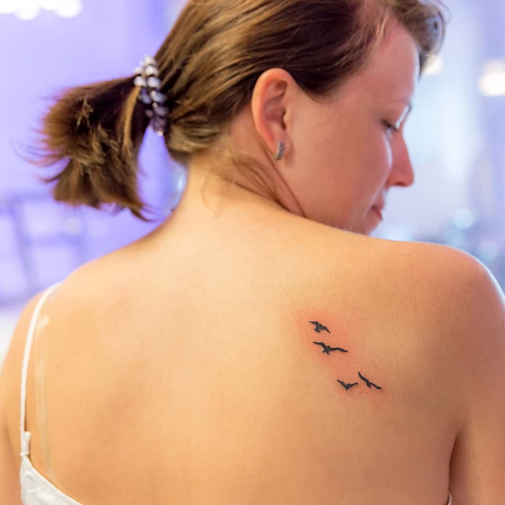 Small Simple Black Birds in Flight arranged in a Diagonal Pattern Shoulder Blade Tattoo | selftattoo.com