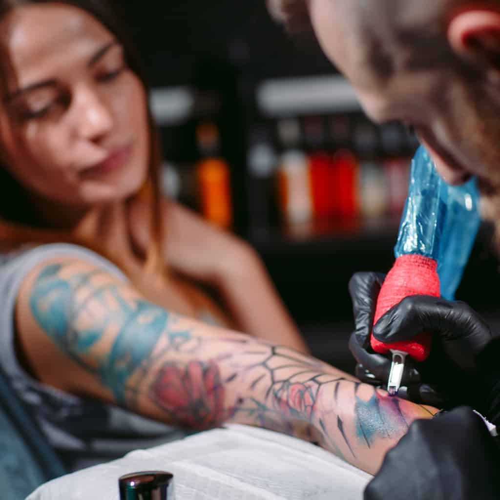 Sleeve Tattoo being worked on featuring a mix of Bright Colors and Bold Black Outlines | selftattoo.com