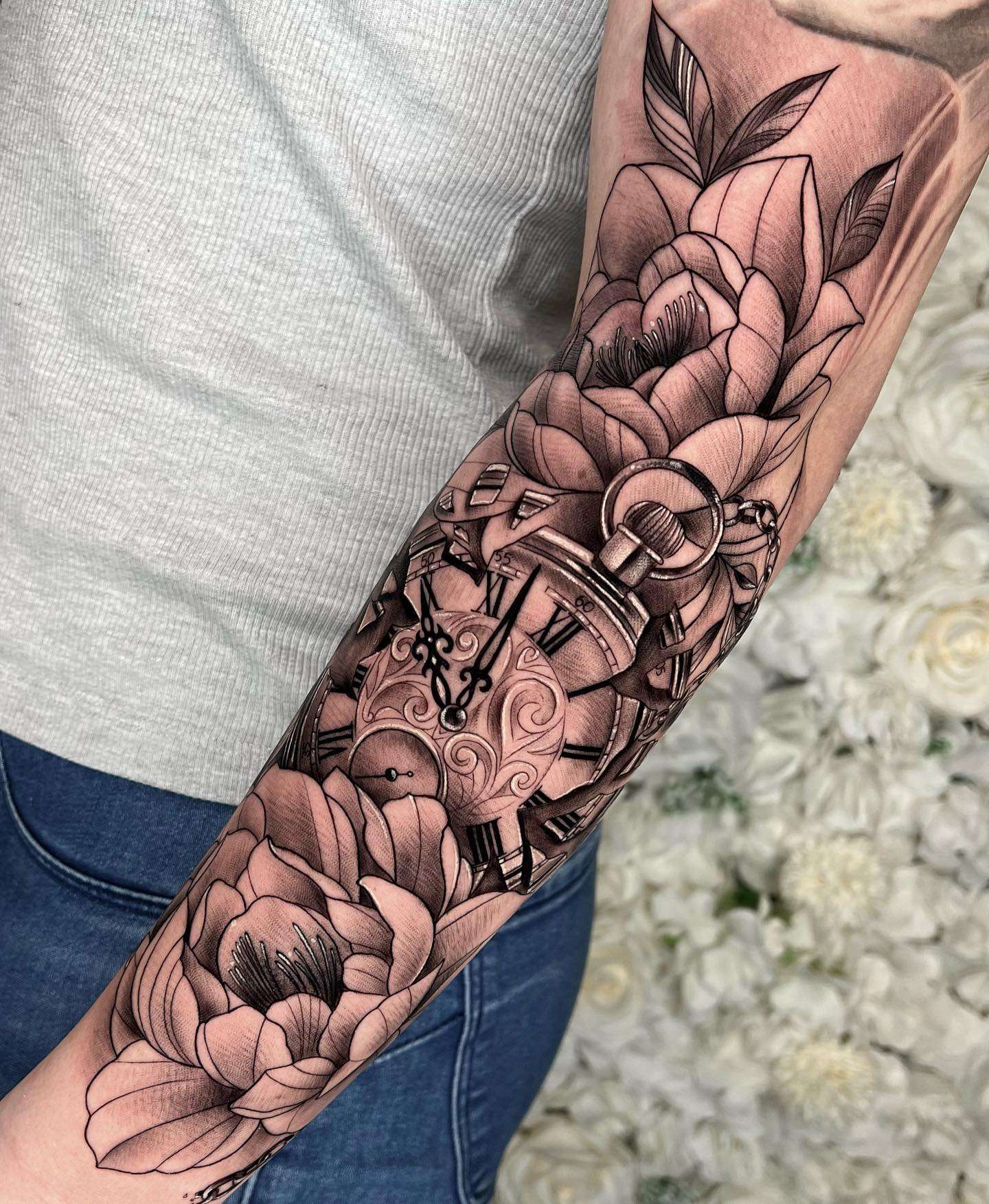 Realistic Black and Gray Pocket Watch Tattoo surrounded by Two Large Flowers | selftattoo.com