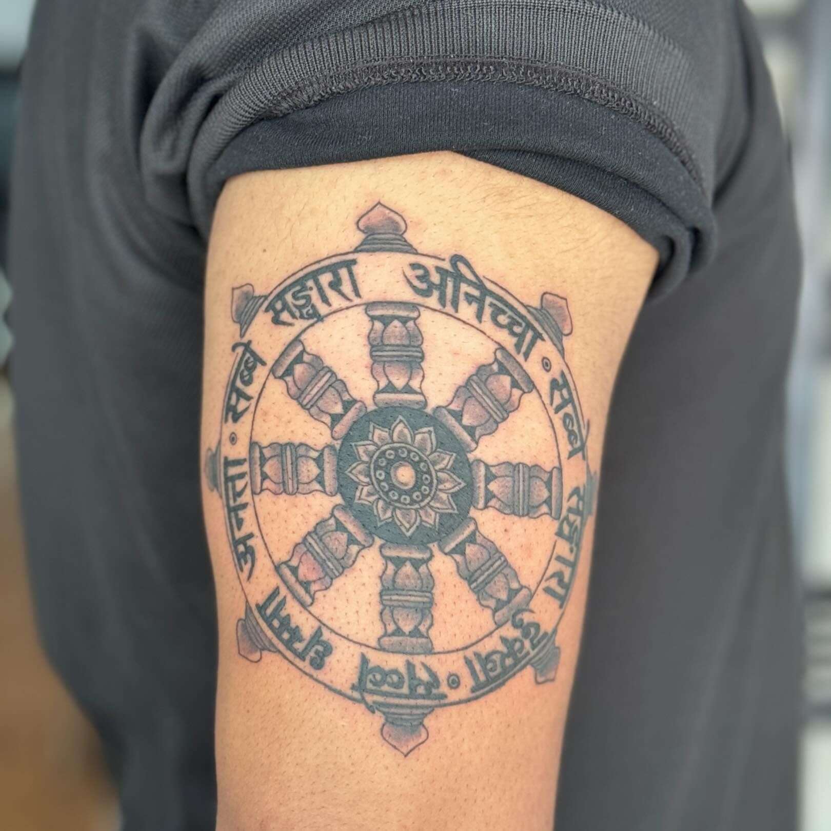 Bold Detailed Linework of a Dharma Wheel Tattoo with Devanagari Script | selftattoo.com