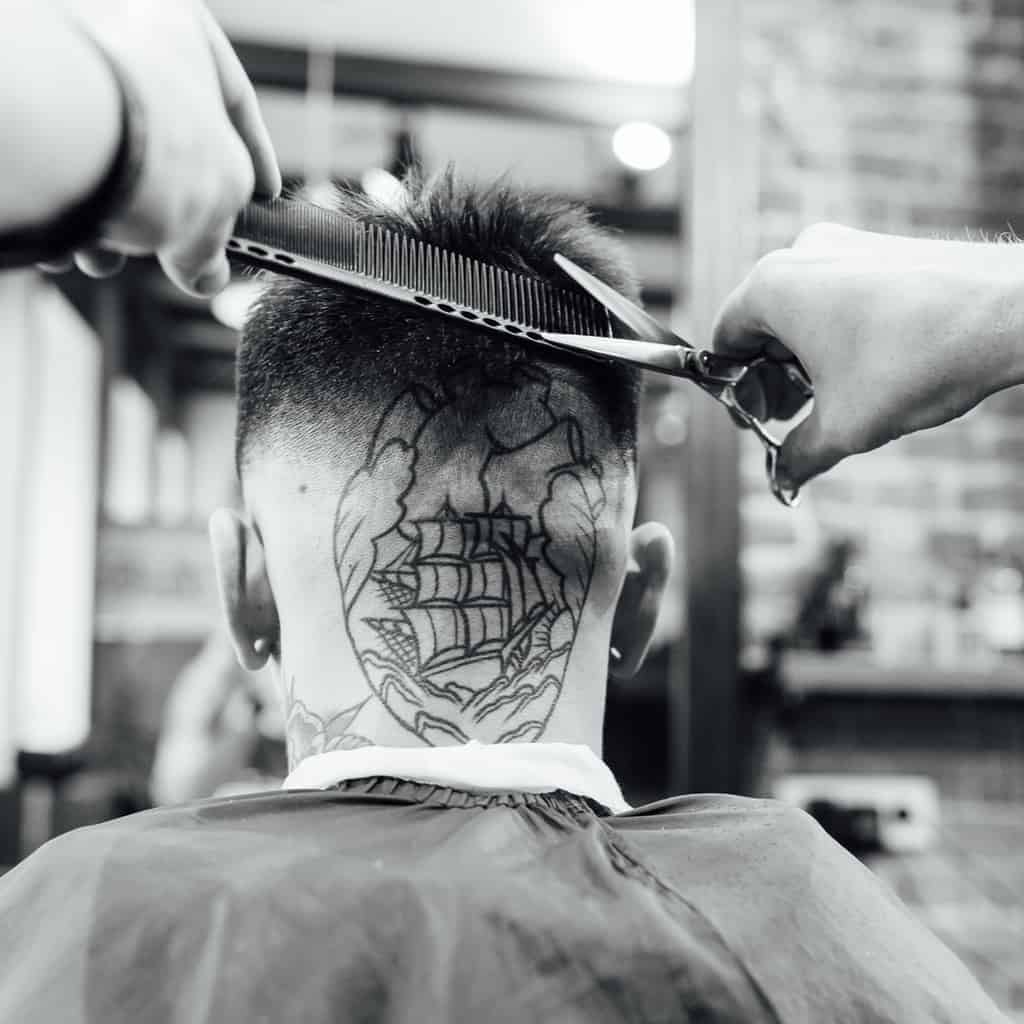 Bold Black Linework of an American Traditional Style Ship inside a Heart Behind the Head Tattoo | selftattoo.com