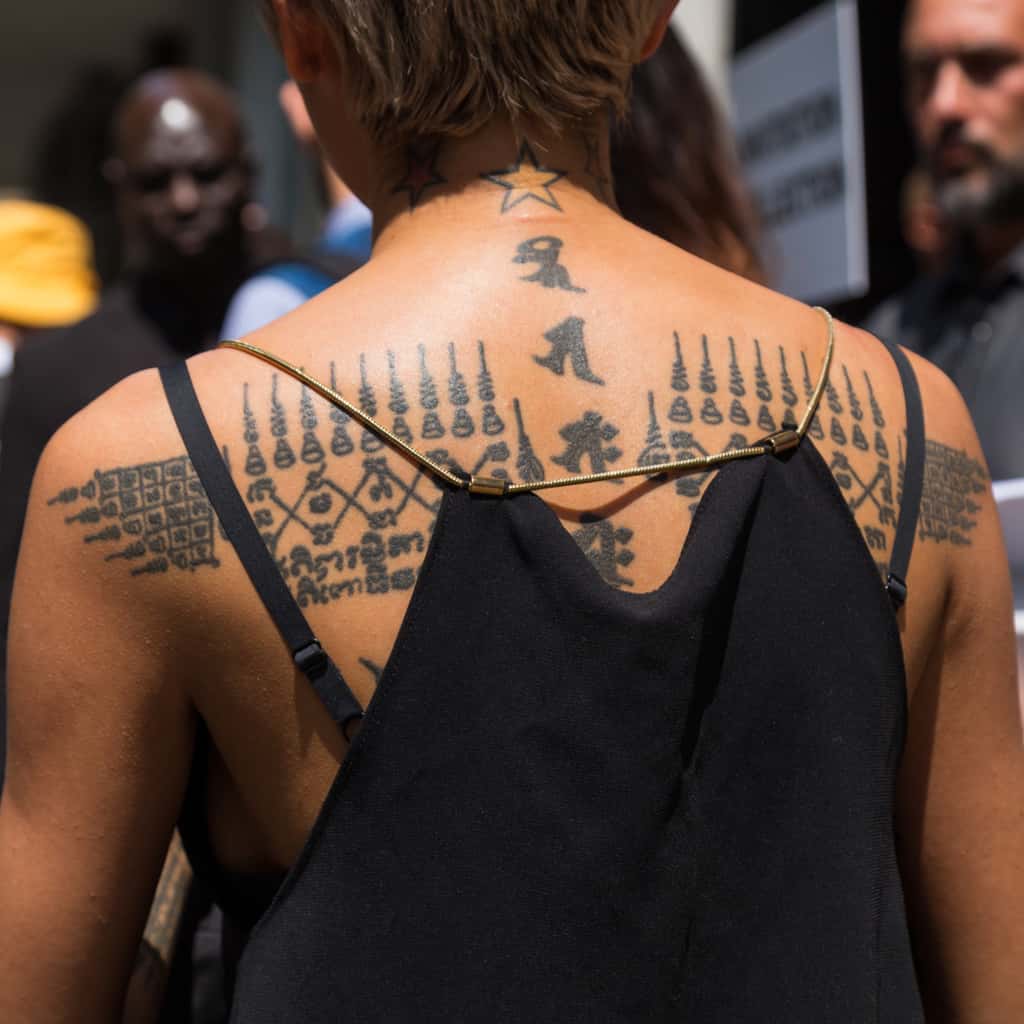 Bold Black Traditional Sak Yant Upper Back Tattoo featuring Rows of Sacred Patterns and Symbols | selftattoo.com
