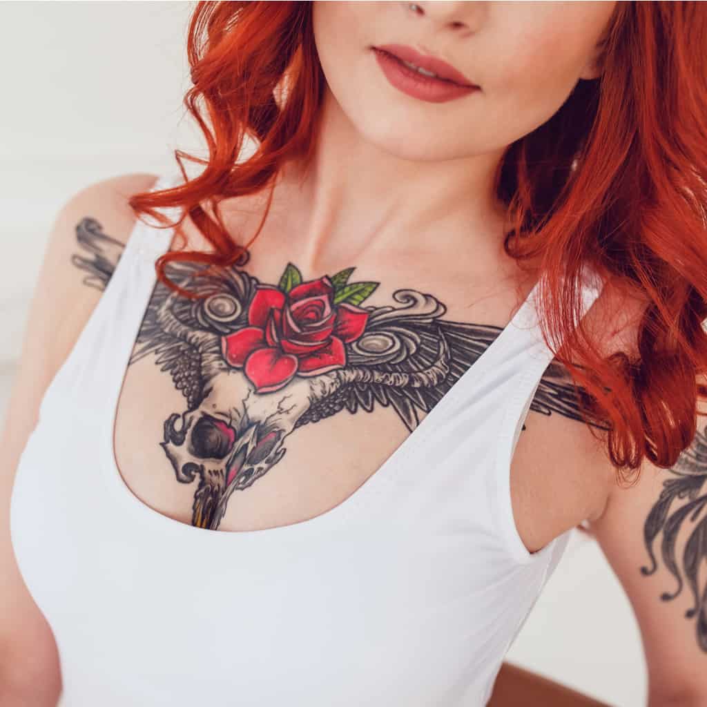Vibrant Red Rose and a Winged Skull with Bold Black Linework Upper Chest Tattoo | selftattoo.com