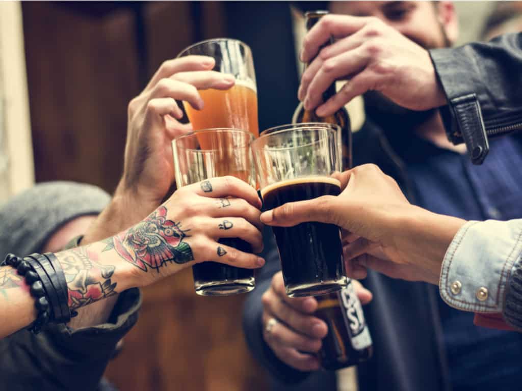 A Group of People raising their Glasses in a Toast with one person showcasing Vibrant Tattoos | selftattoo.com