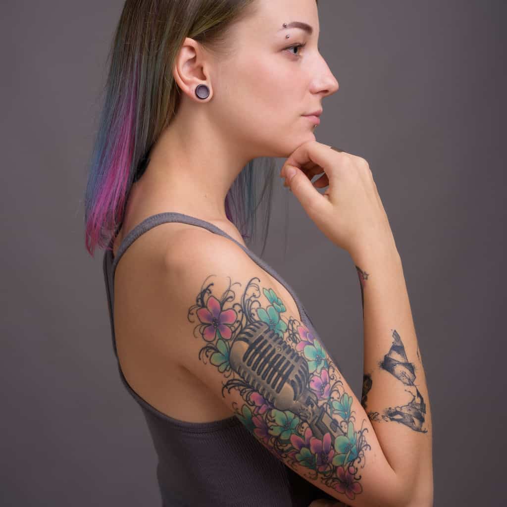 Realistic Vintage Microphone Upper Arm Tattoo surrounded by Pink and Blue Flowers | selftattoo.com