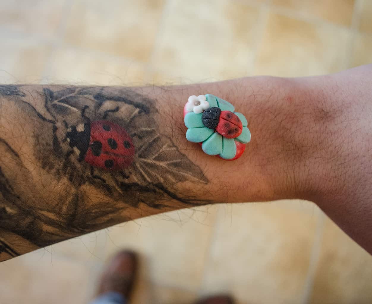 Red Ladybug amidst a Background of Black and Gray Leaves Forearm Tattoo | selftattoo.com