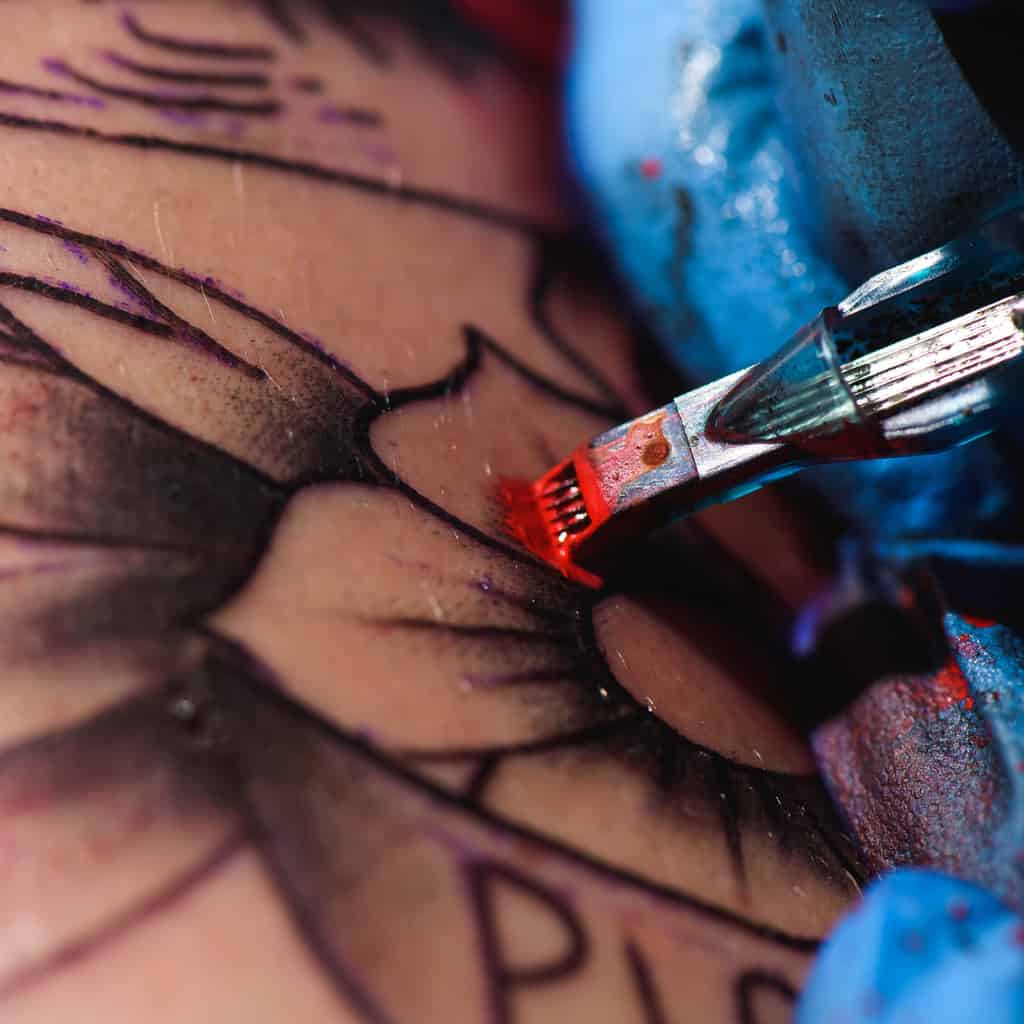 Close-Up of a Tattoo Needle Injecting Red Ink into the Skin | selftattoo.com