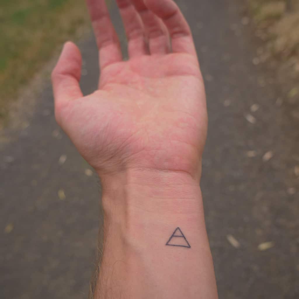 Small Black Triangle Outline with a Line in the Middle Wrist Tattoo | selftattoo.com