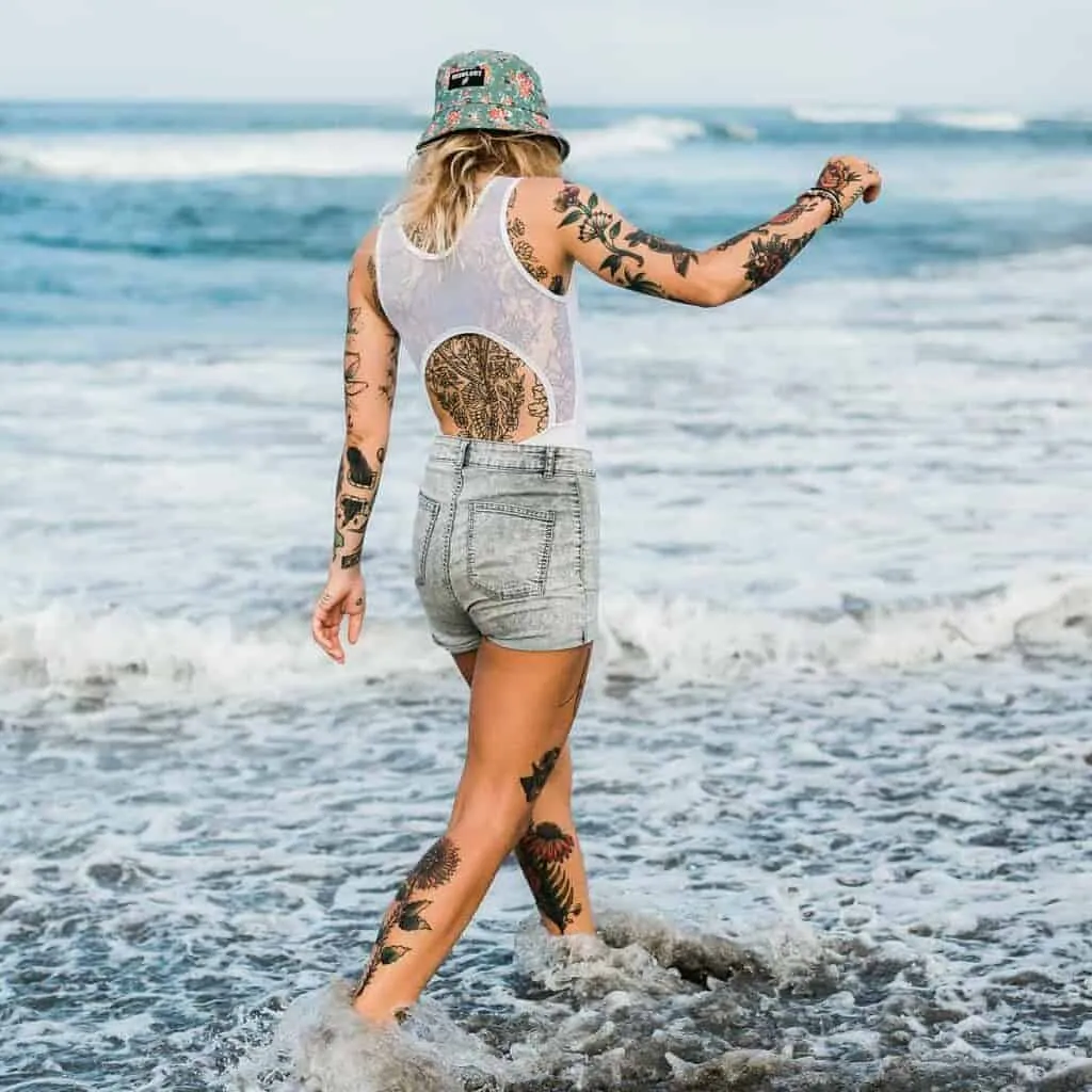 Woman Walking by the Ocean covered in Various Tattoos | selftattoo.com