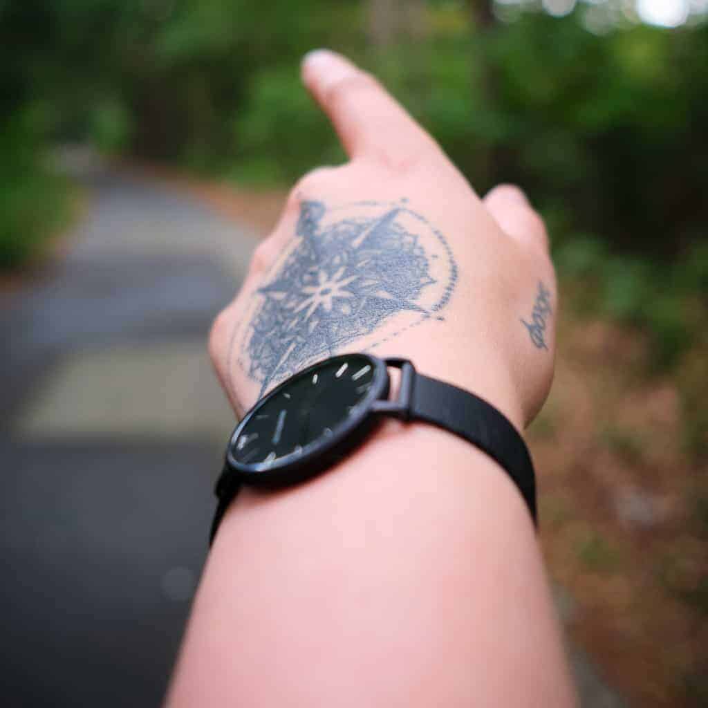 Bold Black Compass radiating Mandala Style Patterns surrounded by a Circle of Dots Hand Tattoo | selftattoo.com