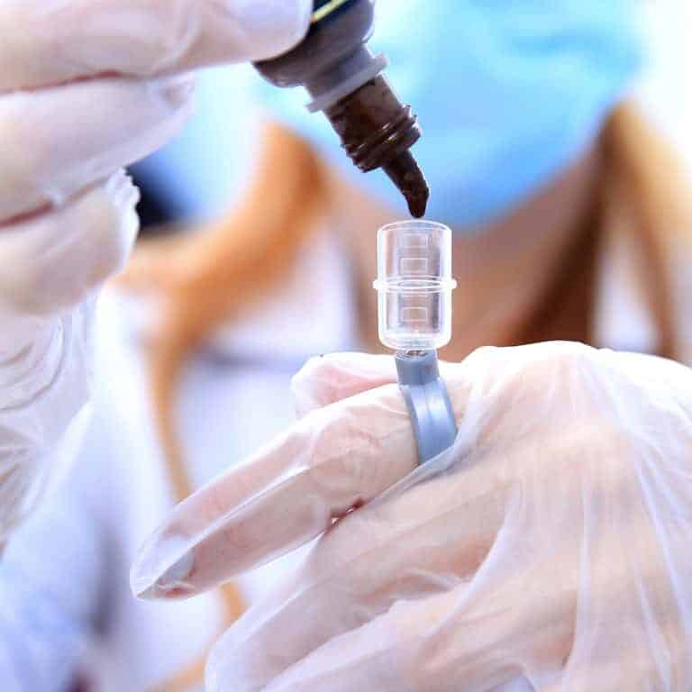 Close-up of a Practitioner pouring Tattoo Ink into a Small Clear Container | selftattoo.com