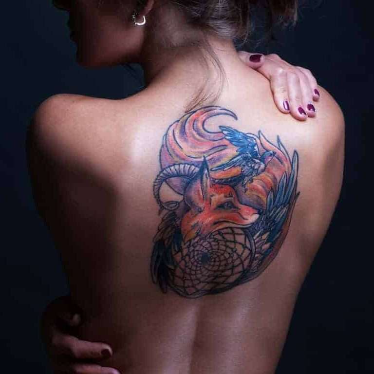 Fox Tattoo With Ram Horns and a Bird in Flight, All Encircled by a Dreamcatcher on the Upper Back | selftattoo.com